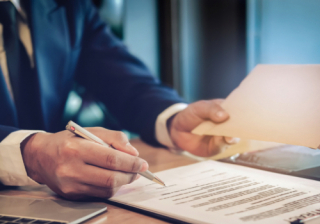 Person signing a document with a pen