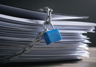 pile of paper documents with a chain and padlock around