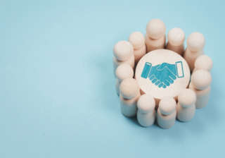 Wooden figures stood in a circle around a picture of a fist on a blue background