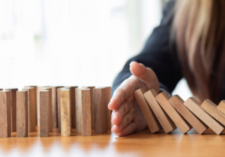 hand stopping chain reaction of wooden blocks falling over