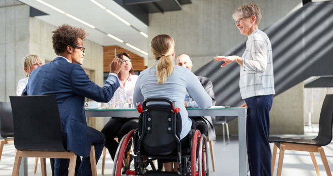 Group of people working around a desk, with one person in a wheelchair