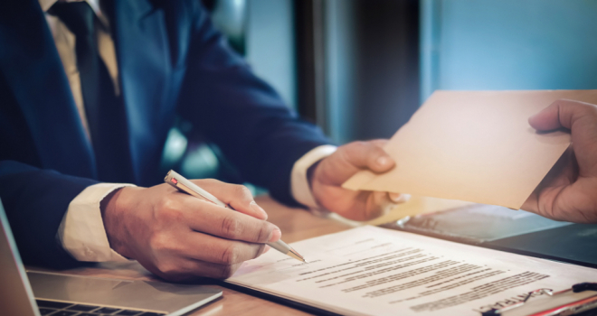 Person signing a document with a pen