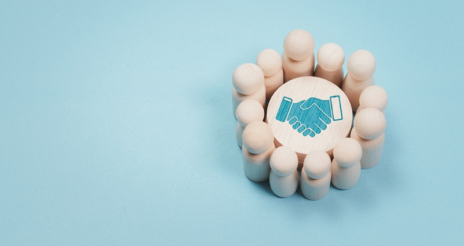 Wooden figures stood in a circle around a picture of a fist on a blue background